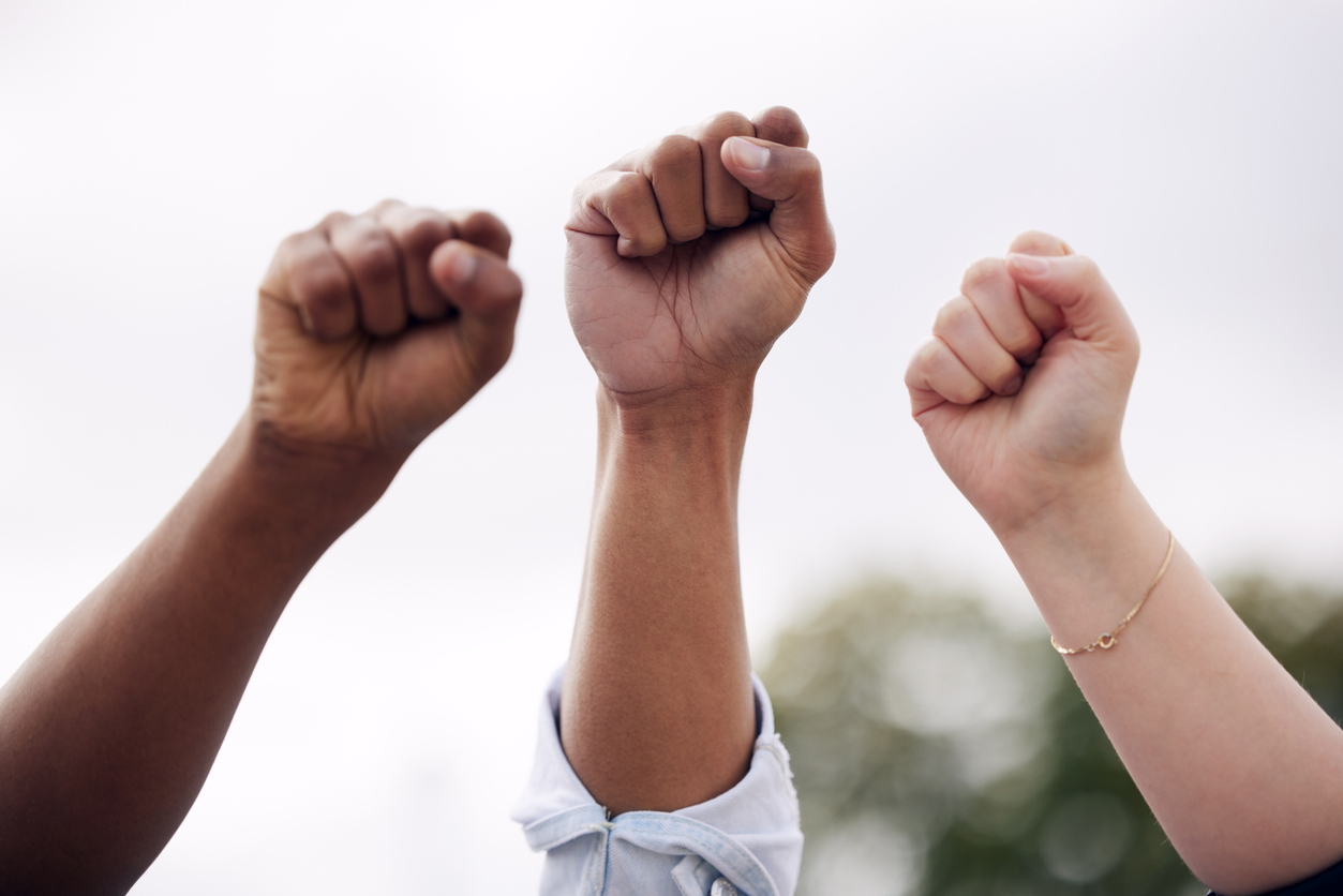 Shot of a group of students raising their fists in protest outside